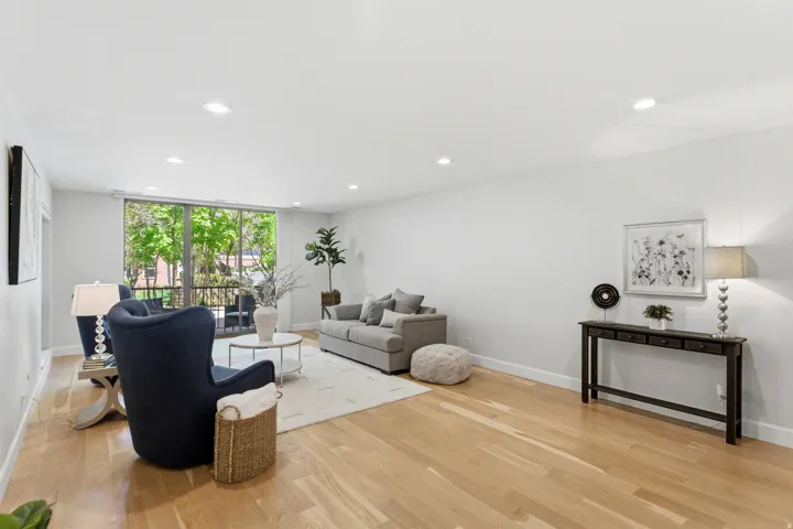 Hardwood flooring throughout, recessed lighting, and a full-height glass panel balcony door