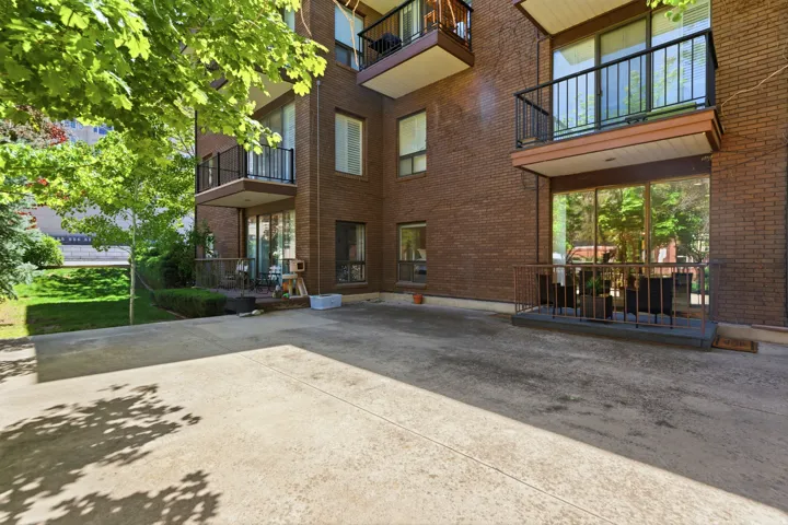 Brick exterior with multiple balconies featuring black metal railings and overhead canopies