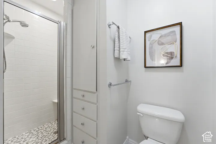 Glass-enclosed shower with subway tile surround and pebble tile flooring