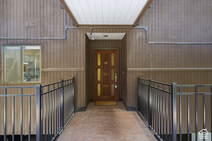 Wood-paneled exterior with a decorative entry door, protected by a covered walkway