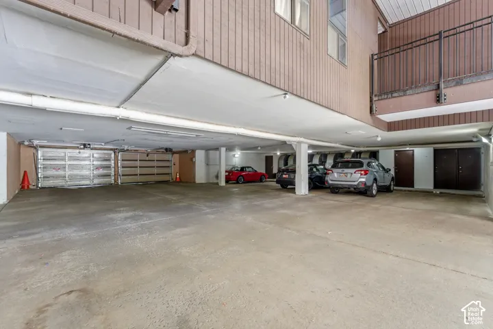 Covered parking area with concrete flooring, multiple support columns, and overhead lighting