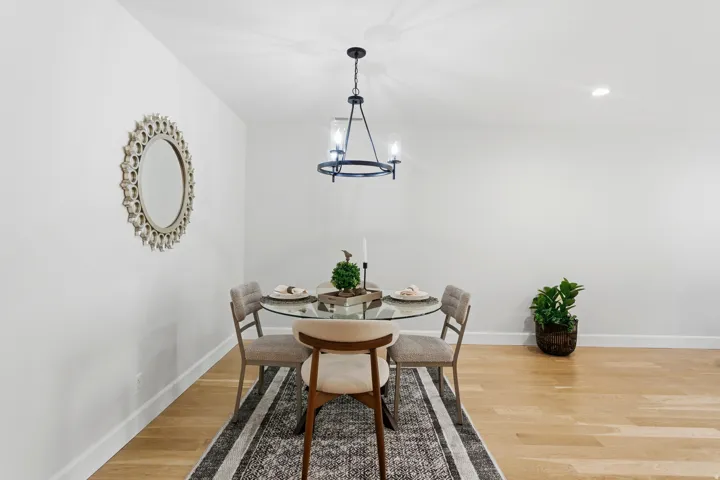 Light wood-finish flooring, recessed lighting, and a modern chandelier with a matte black finish
