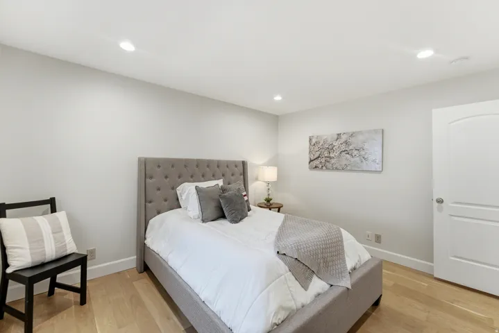Light wood-finish flooring, recessed lighting, and a white interior door with an arched panel