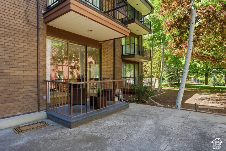 Brick exterior with multiple balconies, a ground-level patio, and sliding glass doors