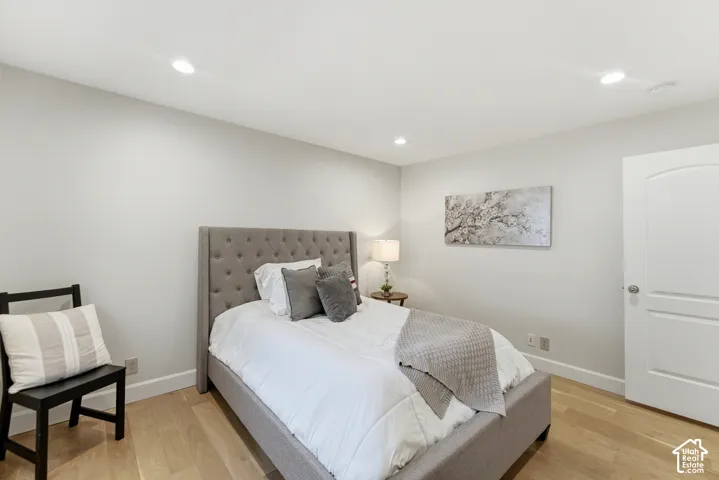 Light wood-finish flooring, recessed lighting, and a white interior door with an arched panel