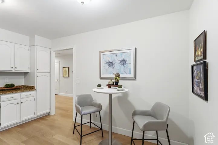 White cabinetry with brushed nickel hardware, granite countertops, light wood-finish flooring, and recessed lighting