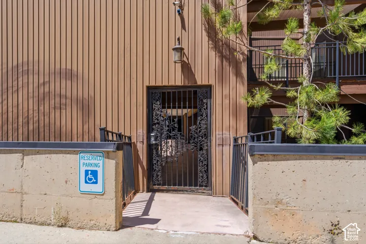 Ramped entry with wrought iron gate, featuring vertical siding and metal railings