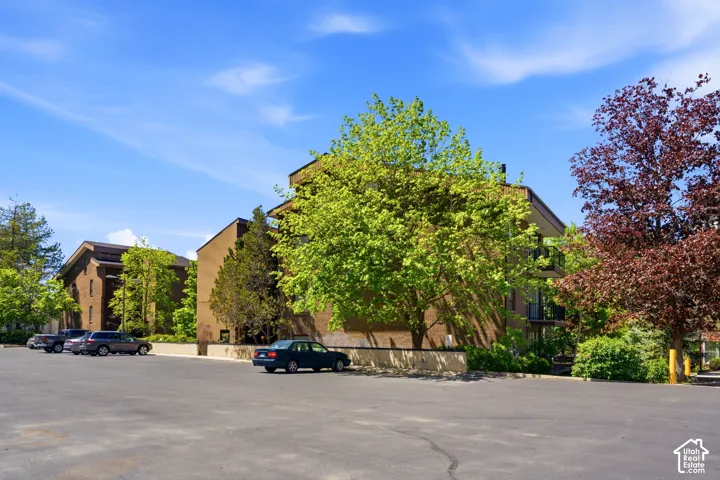 Brown brick exterior building with multiple balconies and surrounding mature trees