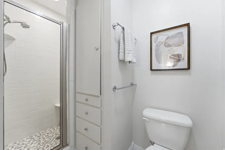 Glass-enclosed shower with subway tile surround and pebble tile flooring