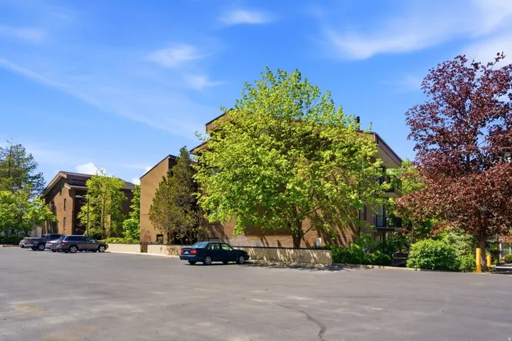 Exterior architecture featuring brick and stucco finishes, multiple balconies, and mature landscaping