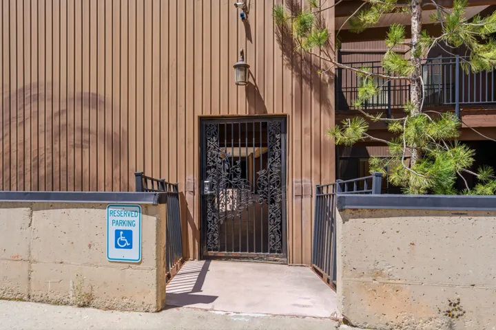 Ramped entry with wrought iron gate, featuring vertical siding and metal railings