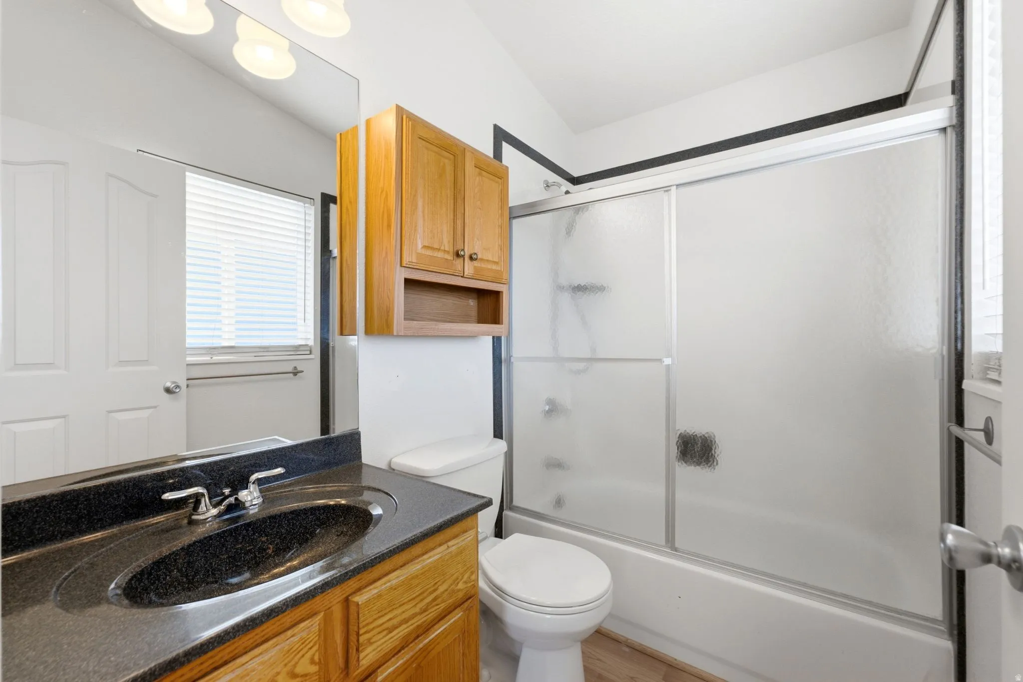 Bathroom featuring a vanity with dark countertop, integrated sink, and wood-finish cabinetry