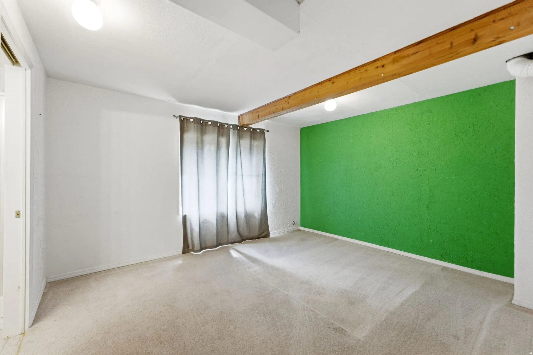 Exposed wood beam, recessed lighting, wall-to-wall carpeting, and bright accent wall