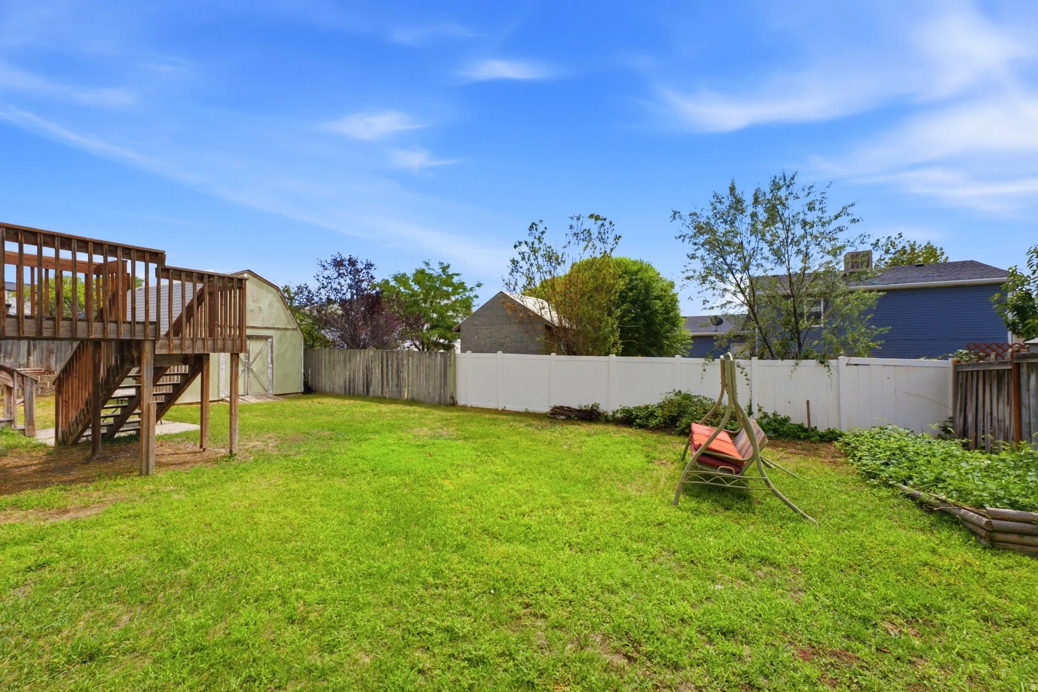 Expansive grassy yard area with a multi-level wooden deck structure