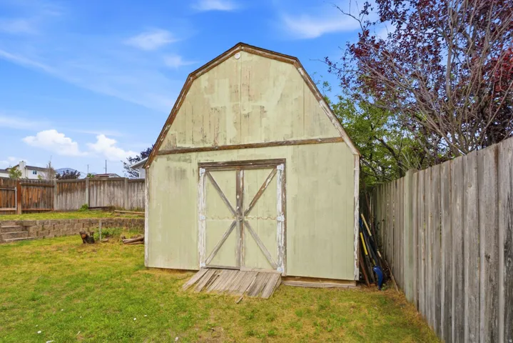 Gabled storage shed with double doors, wood-plank siding, and an aged finish