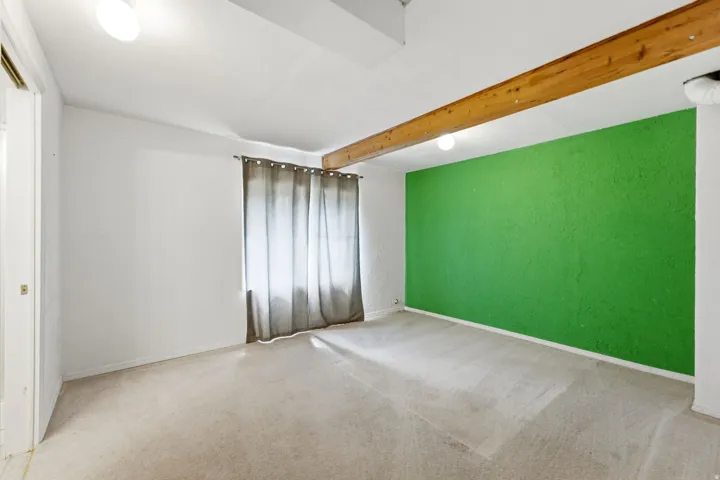 Exposed wood beam, recessed lighting, wall-to-wall carpeting, and bright accent wall