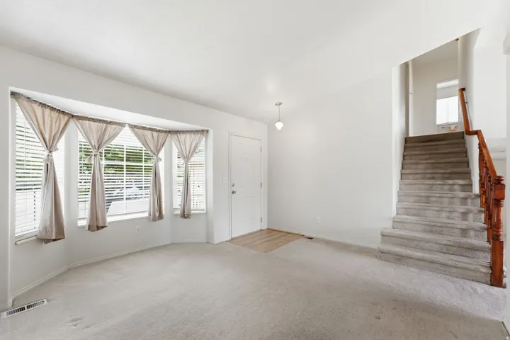 Bay window with blinds, carpeted flooring, wood-finish flooring, staircase with wood railing, recessed lighting