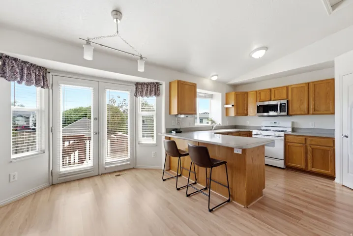 Kitchen with light wood-finish flooring, wood cabinetry, and a central island with a light-toned countertop