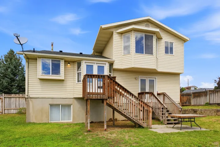 Beige siding exterior with a two-story design, featuring bay windows and two wooden deck staircases