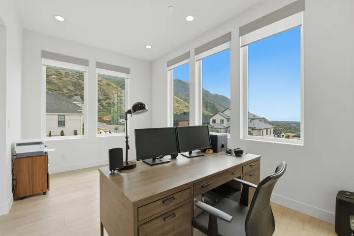 Recessed lighting, wood-finish flooring, and multiple large windows with roller shades
