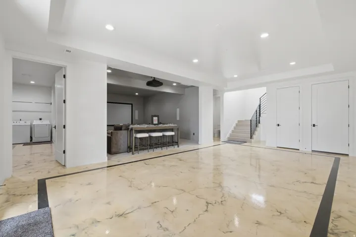 Expansive polished flooring with contrasting border, recessed lighting, and a dedicated laundry area