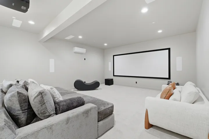 Entertainment room featuring a large projection screen, recessed lighting, and wall-mounted speakers