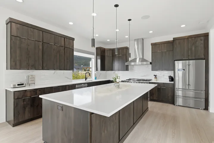 Gourmet kitchen with dark wood-finish cabinetry, stainless steel appliances, white countertops, and a large central island