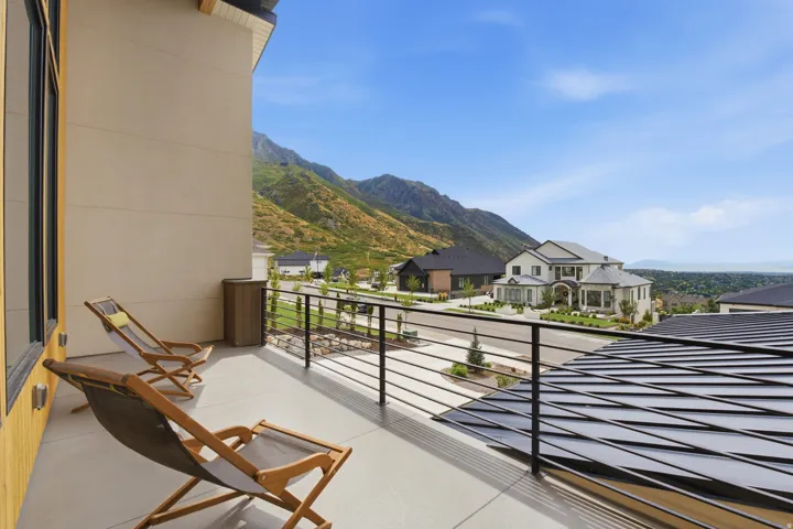 Balcony with a flat parapet wall, black metal railing, and engineered wood siding