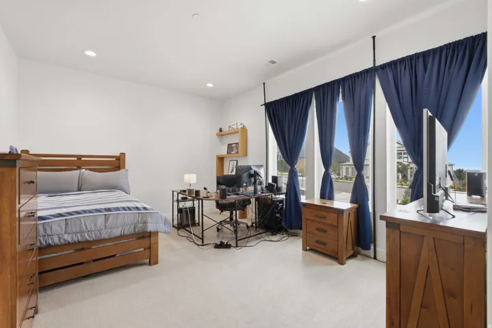 Recessed lighting, light neutral-toned carpet, and a large window wall with multiple vertical windows