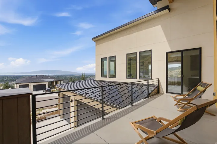 Expansive balcony featuring a concrete surface, black metal railing, and sliding glass door access