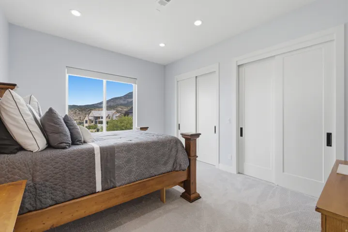 Expansive window with mountain scenery, recessed lighting, two white sliding closet doors, and light gray patterned carpeting