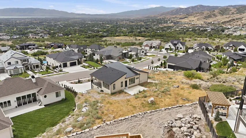 Contemporary residential architecture with dark roofing, a prominent mountain backdrop, and established neighborhood landscaping
