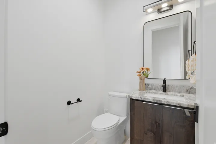 Modern vanity with dark wood-finish cabinetry, light-toned countertop, rectangular sink, and matte black faucet