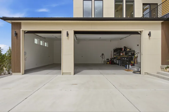 Integrated two-car garage with concrete flooring, transom windows, and exterior wall-mounted lighting