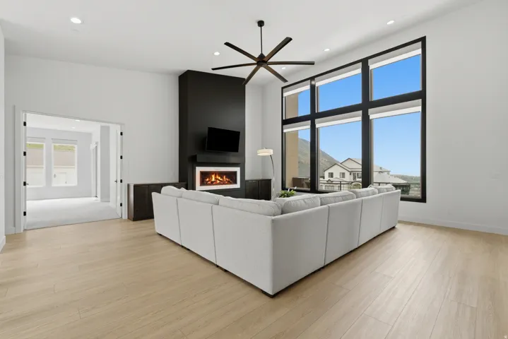 Vaulted ceilings, wood-finish flooring, and a linear fireplace with a dark surround