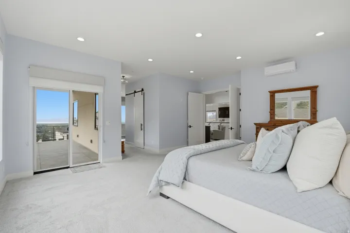 Sliding glass door to an outdoor patio, recessed lighting, wall-mounted air conditioning unit, and a barn door entry
