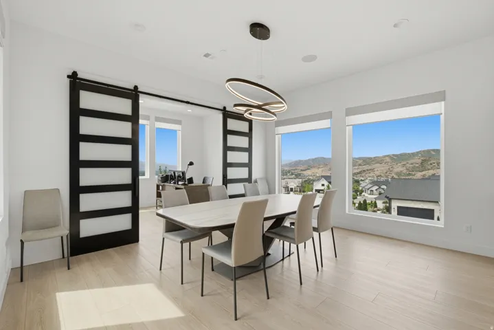Expansive windows, wood-finish flooring, modern chandelier, recessed lighting, and barn doors