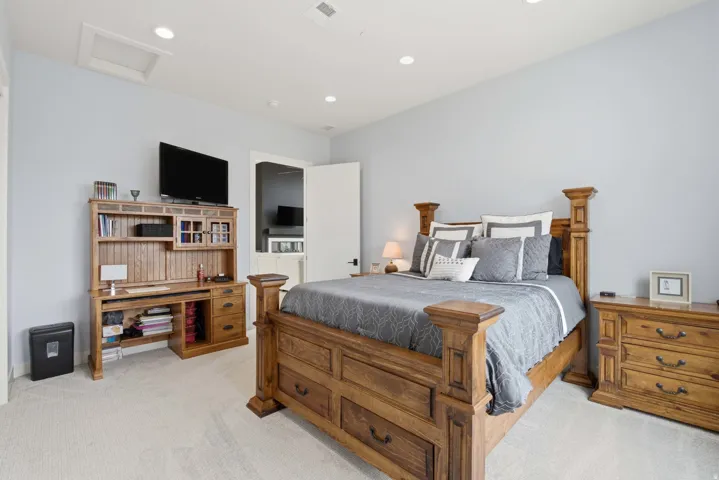 Recessed lighting, light-colored carpeting, light blue wall paint, and a white door with black hardware