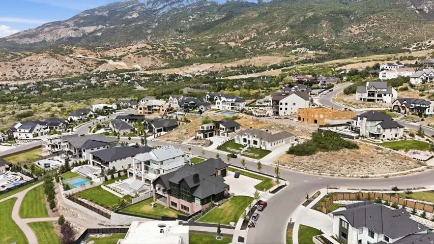 Mountainous backdrop, residential development, varied architectural styles, paved roads, natural landscaping