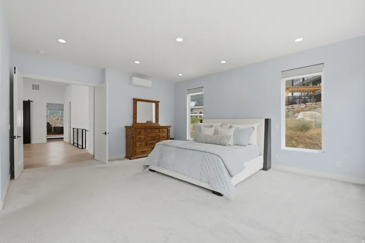 Recessed lighting, light-toned carpeting, multiple windows, and a built-in mini-split unit