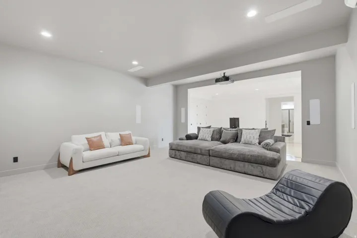 Recessed lighting, ceiling-mounted projector, wall-mounted speakers, and light-toned carpeting