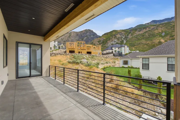 Covered patio with concrete flooring, black metal horizontal railings, and sliding glass doors