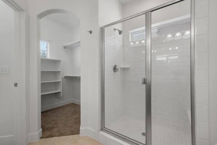 Walk-in shower with clear glass enclosure and subway tile surround