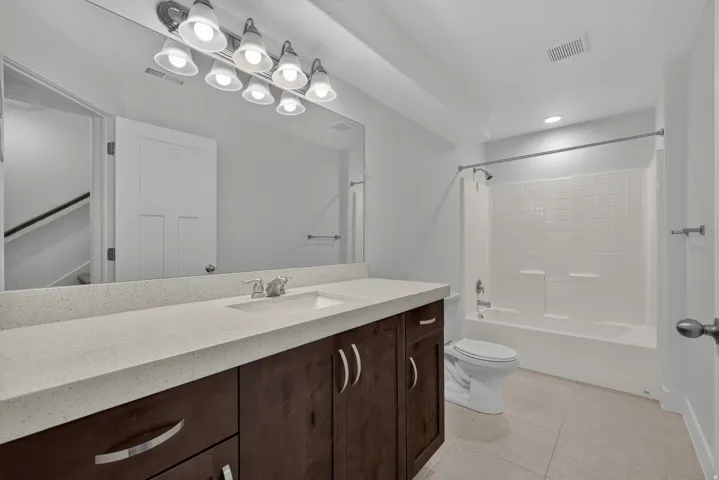 Vanity with a light-toned countertop, wood-finish cabinetry, and a large mirror