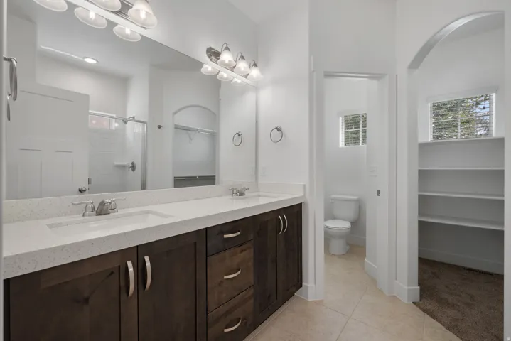 Dual vanity with white countertops, wood-finish cabinetry, and brushed nickel fixtures