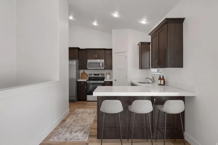 Kitchen featuring dark wood-finish cabinetry, stainless steel appliances, and light-toned countertops