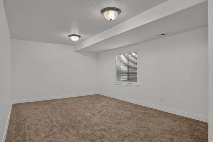 Recessed ceiling lights, neutral wall paint, white window trim, horizontal window blinds, and carpet flooring