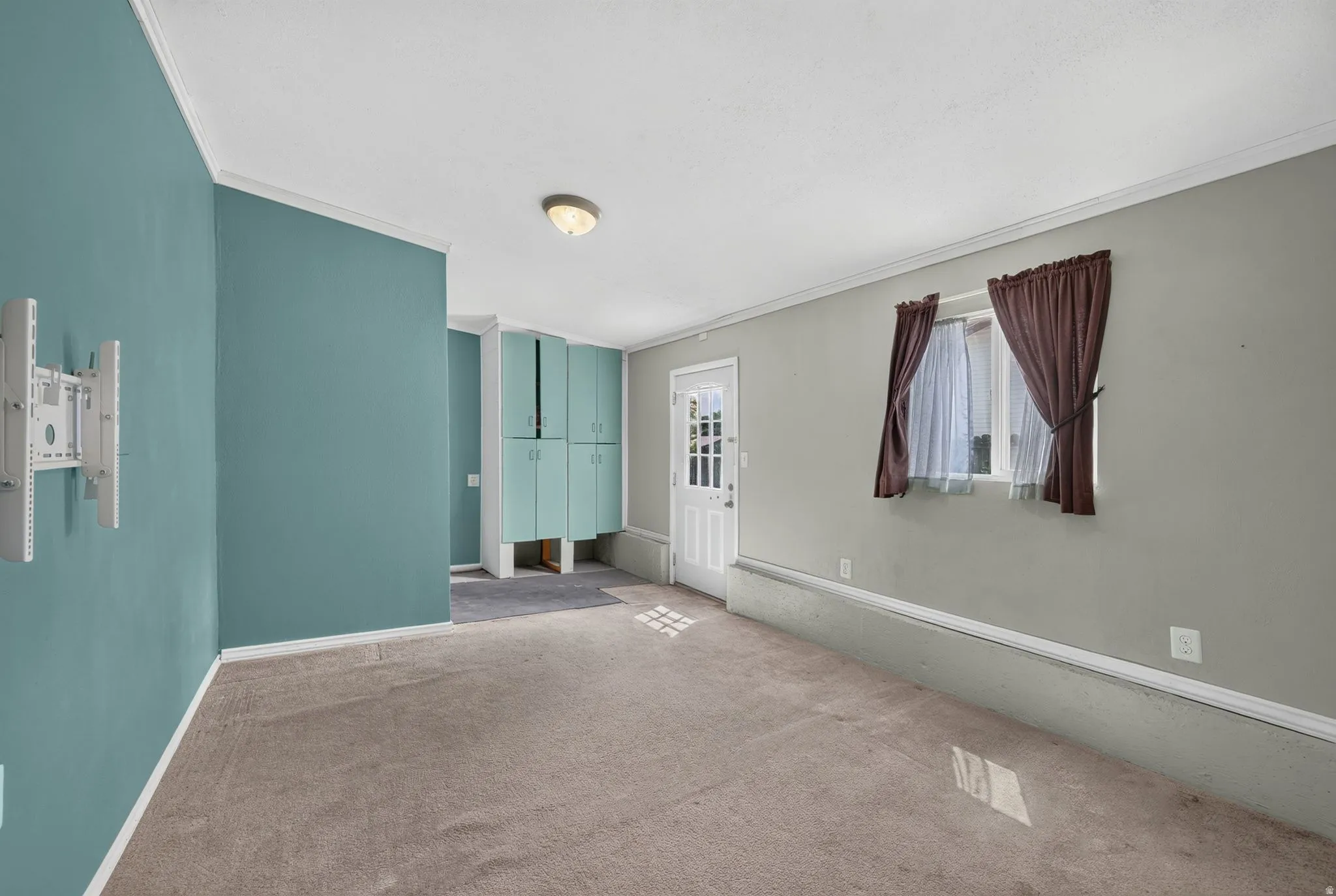 Carpeted room featuring a white paneled door with glass inserts, recessed lighting, and built-in teal cabinetry