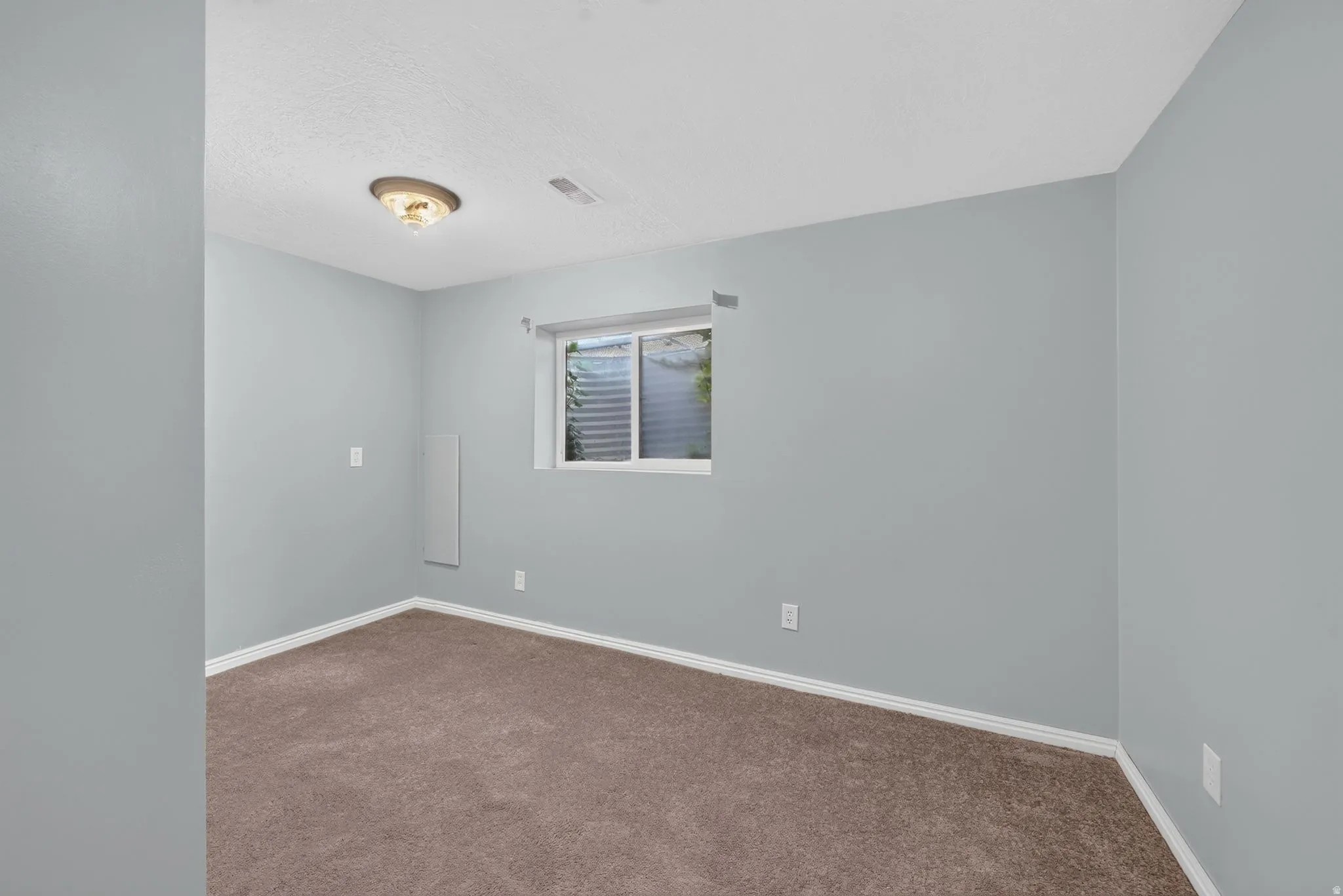 Light gray painted walls with a window, wall-to-wall carpeting, and a flush mount ceiling light