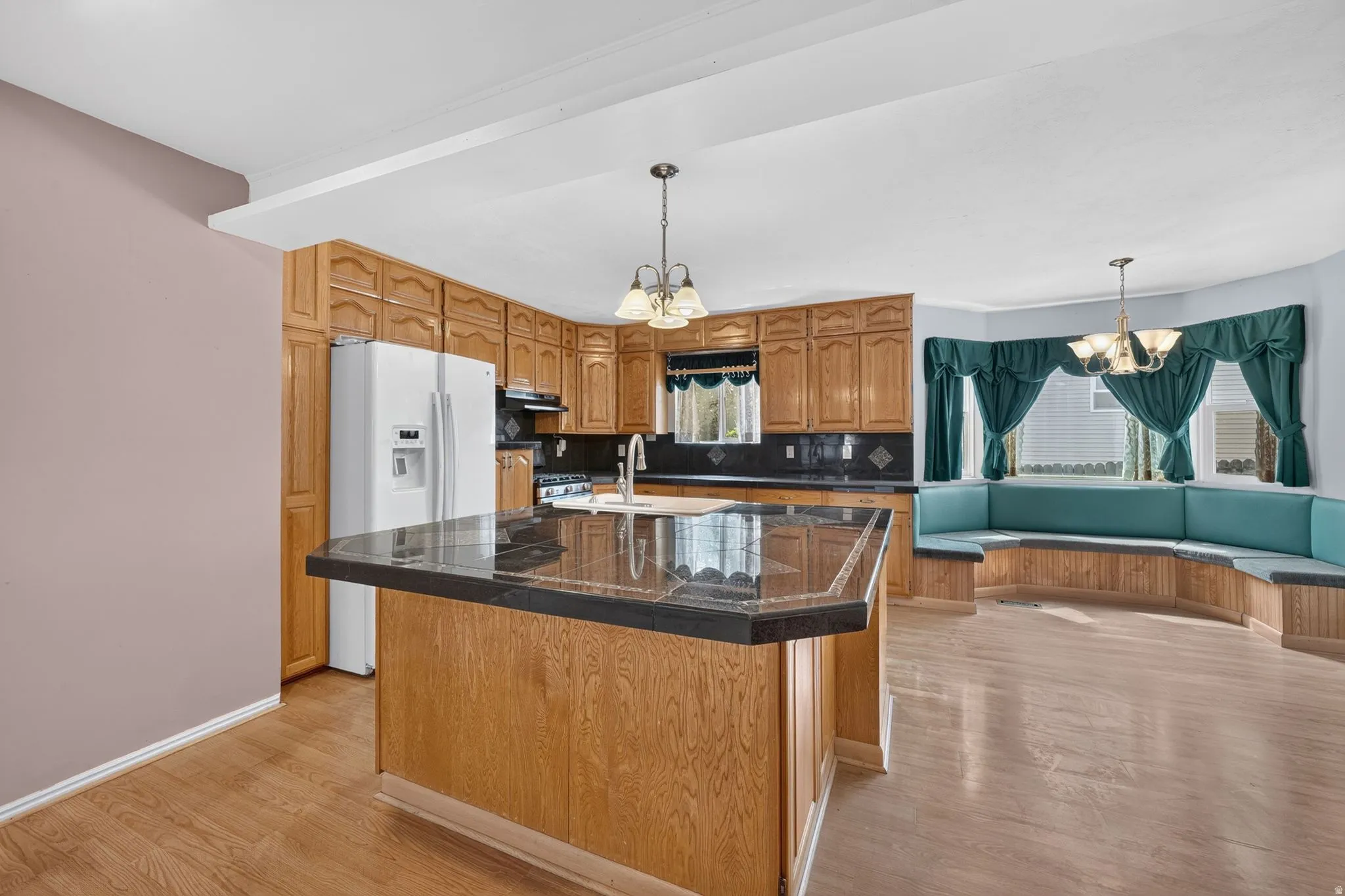 Kitchen featuring wood cabinetry, a center island with a dark countertop, stainless steel appliances, and wood-finish flooring